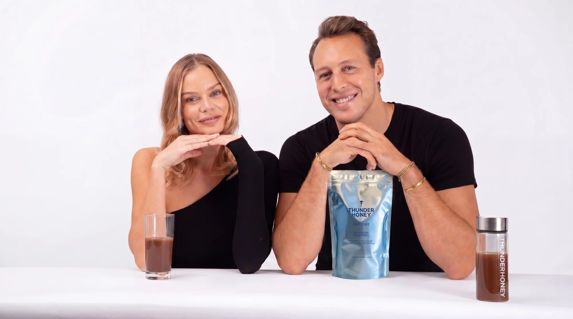 Joakim Bjarke and Nina Strauss, the founders of Thunder Honey, at a table with a Daylight pouch and a glass of the cacao drink