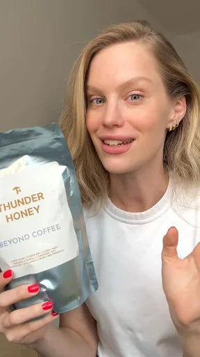 A young woman in a white t-shirt holding up a pouch of Thunder Honey and talking to the camera