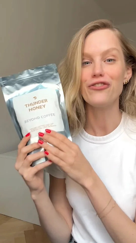A young woman in a white t-shirt holding a pouch of Thunder Honey up beside her face and talking to the camera